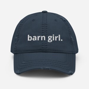 May include: A distressed navy blue baseball cap with the embroidered text "barn girl." The cap has a pre-worn look with distressed edges and a curved brim. A casual accessory for everyday wear.