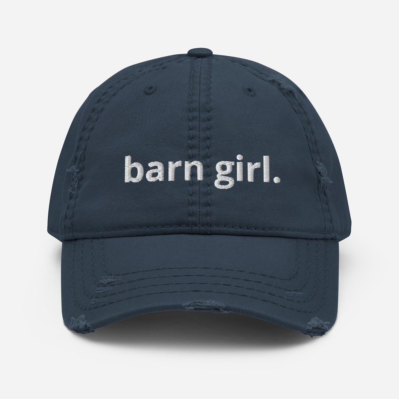 May include: A distressed navy blue baseball cap with the embroidered text "barn girl." The cap has a pre-worn look with distressed edges and a curved brim. A casual accessory for everyday wear.