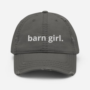 May include: A distressed gray baseball cap with the embroidered text "barn girl." The hat has a pre-worn look with distressed edges and stitching details. A casual accessory for everyday wear.
