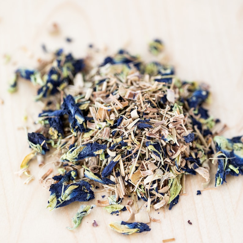 May include: A close-up of a blend of dried herbs and flowers for tea. The mixture includes blue butterfly pea flowers, lemongrass, and other herbs.