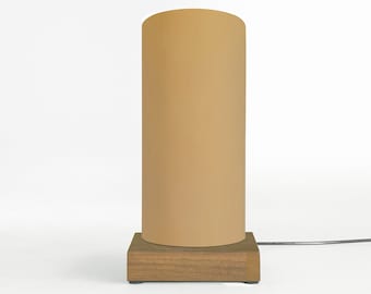 May include: A modern table lamp with a cylindrical beige lampshade and a wooden base.