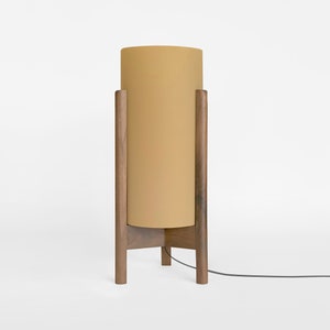 May include: A floor lamp with a wooden base and a cylindrical yellow lampshade.