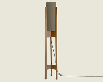May include: A tall wooden floor lamp with a cylindrical gray fabric shade. The lamp has a black cord with a foot switch.