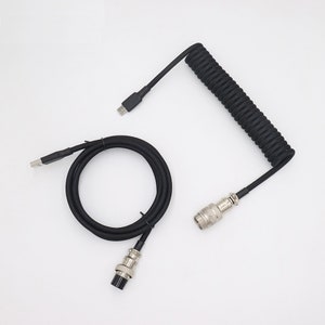 May include: A black coiled cable with a USB-A connector on one end and a metal connector on the other end. The cable is coiled and has a black braided outer covering.