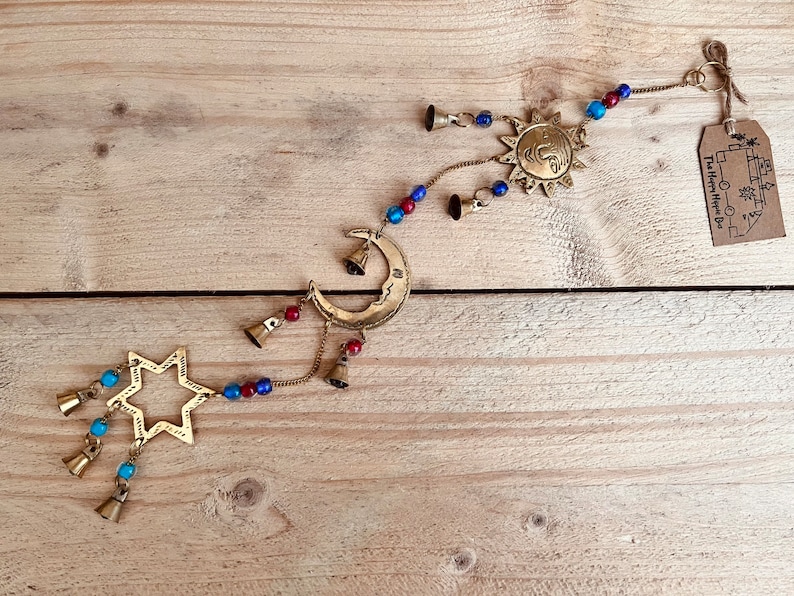 Brass wind chime with a crescent moon, star, and sun design. The chime has blue and red beads and bells. Handmade Fair Trade Ethically Sourced Bohemian Hippie Bell