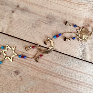 Brass wind chime with a crescent moon, star, and sun design. The chime has blue and red beads and bells. Handmade Fair Trade Ethically Sourced Bohemian Hippie Bell