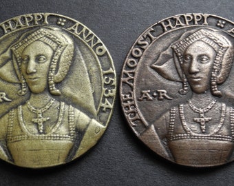 May include: Two bronze medallions depicting a woman in a crown and a necklace. The medallions are inscribed with the text "The Most Happy Anno 1534" and "The Most Happy Anno 1534".