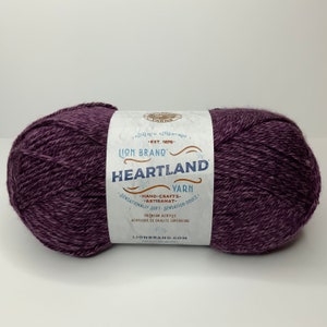 May include: A skein of Lion Brand Heartland yarn in the color Plum. The label reads "Authentic Authentique - Est. 1878 - Lion Brand Heartland Yarn - Hand-Crafts - Artisanat - Sensationally Soft - Sensation Douce - Premium Acrylic - Acrylique de Qualite Superieure - LionBrand.com".