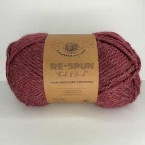 May include: A skein of Lion Brand Re-Spun Thick & Quick yarn in a deep burgundy color. The label reads "100% Recycled Polyester" and "Lionbrand.com".