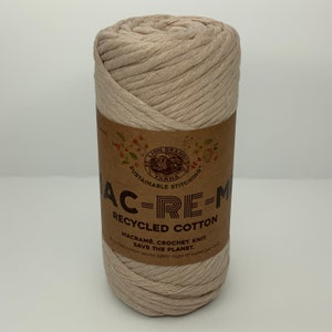 May include: A beige ball of Lion Brand yarn labeled "AC-RE-M Recycled Cotton" with the text "Macrame. Crochet. Knit. Save the Planet. Recycled cotton saves 5900 cups of water per ball."