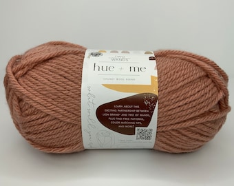 May include: A ball of chunky wool yarn in a warm terracotta color. The label reads "hue + me" and "Two Wands Chunky Wool Blend".