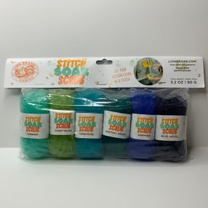 Puede incluir: Seis estropajos de cocina de colores en un paquete de plástico. Los estropajos son en tonos de verde, azul y turquesa. El paquete tiene el texto "Stitch Soak Scrub".