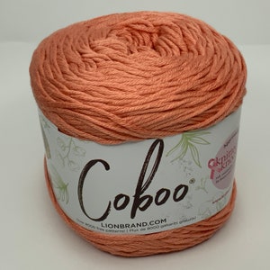 May include: A ball of coral-coloured Coboo yarn with a white label that says "Coboo" and "Lionbrand.com" with the text "Over 8000 free patterns! | Plus de 8000 gabarits gratuits!"