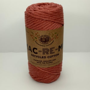 May include: A ball of terracotta colored recycled cotton yarn. The label reads "Lion Brand Yarns, Sustainable Stitching, Mac-Re-Mi Recycled Cotton, Macrame, Crochet, Knit, Save the Planet. Recycled cotton saves 5900 cups of water per ball."