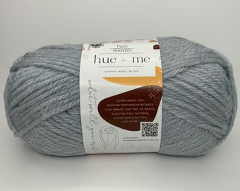 May include: A skein of light gray chunky wool yarn labeled "hue + me" by Two Wands. The label also includes information about a partnership between Lion Brand and Two of Wands, free patterns, color matching tips, and more.