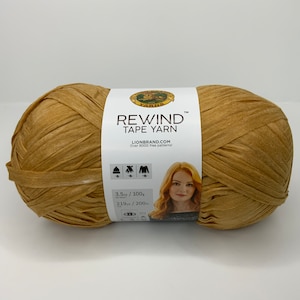 May include: A skein of Lion Brand Rewind Tape Yarn in a brown color. The label reads "Rewind Tape Yarn", "LionBrand.com", "Over 8000 free patterns!" and "3.5 oz / 100g, 219 yds / 200m".