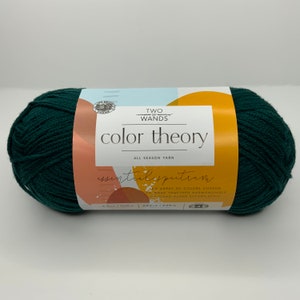 May include: A skein of Two of Wands Color Theory Essential Spectrum yarn in a deep forest green color. The label reads "Two of Wands Color Theory All Season Yarn Essential Spectrum An array of colors chosen to work together harmoniously and stand alone effortlessly 4.5 oz/100 g 246 m/225 m."