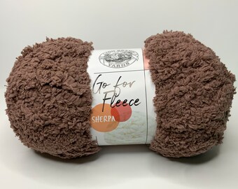 May include: A skein of brown Go for Fleece Sherpa yarn. The yarn is soft and fluffy, and it is perfect for making blankets, scarves, and other cozy items.