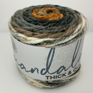 May include: A skein of Mandala Thick & Quick yarn in a multi-colored pattern of brown, gray, white, and orange.