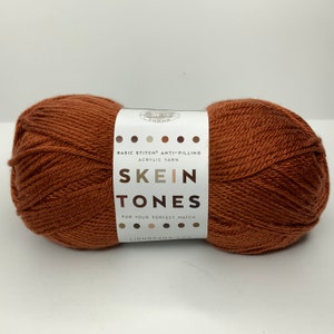 May include: A skein of Lion Brand Basic Stitch Anti-Pilling acrylic yarn in the colour "Tones". The yarn is a deep orange-brown colour.