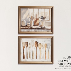 Può includere: Due dipinti incorniciati a tema cucina. Il dipinto superiore raffigura utensili da cucina e un tagliere su un davanzale. Il dipinto inferiore mostra vari utensili da cucina in legno. Entrambi i dipinti hanno una calda tavolozza di colori neutri e sono incorniciati in oro.