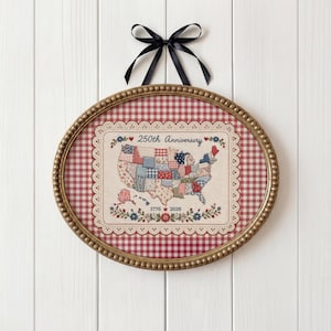 May include: An oval framed textile art piece featuring a map of the United States, composed of patchwork fabric. The frame is gold-toned with a beaded edge, and the background is red and white gingham. A black ribbon is tied at the top.