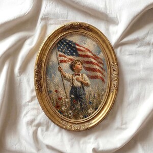 May include: Oval, gold-framed painting depicting a young person holding the American flag in a field of wildflowers. The painting has a vintage aesthetic, with a boy wearing suspenders and a bow tie. The flag is red, white, and blue.