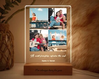 May include: A wooden photo frame with a clear acrylic insert displaying four photos of two women. The photos show the women in a car, playing guitar, and smiling. The frame has a light that illuminates the photos. The text "A sweet friendship refreshes the soul." is written on the frame, along with the names "Sophia & Hannah". The base of the frame has the text "I'm always here for you."