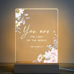 May include: A light-up sign with a floral design and the text "You are the light of the world" with the scripture reference "Matthew 5:14".