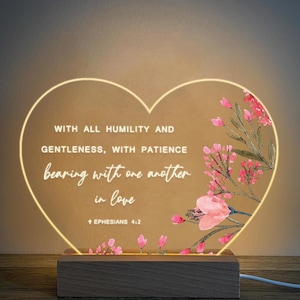 May include: A heart-shaped LED night light with a floral design and the quote "WITH ALL HUMILITY AND GENTLENESS, WITH PATIENCE bearing with one another in love + EPHESIANS 4:2".
