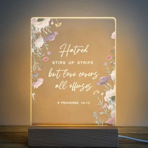 May include: A light-up sign with a floral design and the quote "Hatred stirs up strife but love covers all offenses."  Proverbs 10:12 is printed at the bottom of the sign.