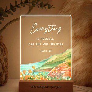 May include: A white LED light sign with a watercolour background of a coastal scene. The sign reads "Everything is possible for one who believes +Mark 9:23". The base of the sign is wood and reads "I'm always here for you".