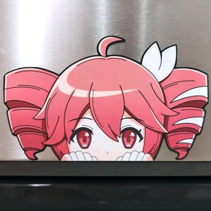 May include: A decorative magnet featuring an anime-style character with vibrant pink hair styled in two large side buns and a small white hair accessory. The character has large red eyes and is depicted with white hands resting at the bottom edge.