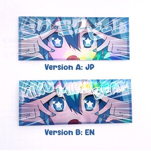 May include: Two rectangular stickers featuring anime-style artwork. The top sticker, labeled "Version A: JP," displays a character with blue hair and eyes, with Japanese text. The bottom sticker, "Version B: EN," shows the same character with English text.