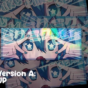 May include: A holographic sticker featuring an anime-style character with blue hair and star-shaped eyes. The character's hands frame their face, with Japanese text above. The sticker has a vibrant color scheme of blues, pinks, and reds.