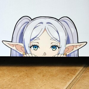 Puede incluir: Una pegatina con un personaje de estilo anime con pelo largo y claro peinado en dos coletas. El personaje tiene ojos grandes y azules, orejas puntiagudas y est&aacute; mirando por encima de una superficie oscura. La pegatina tiene un fondo blanco.