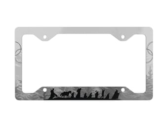 May include: A silver license plate frame with a black and white silhouette of a group of figures walking through a forest. The frame has a gray background with a forest scene.