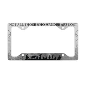 Può includere: Un telaio per targa argentato con un'immagine in bianco e nero di una foresta e il testo "NOT ALL THOSE WHO WANDER ARE LOST". Il telaio ha due fori nella parte superiore e due fori nella parte inferiore per fissare una targa.
