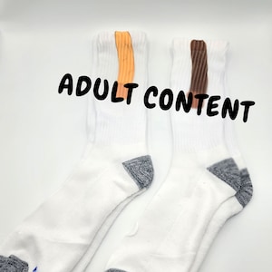 May include: Two pairs of white socks with grey accents at the heel and toe. One pair has an orange stripe and the other has a brown stripe.
