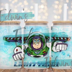 May include: A white tumbler with a blue and green watercolor background featuring a cartoon image of Buzz Lightyear from the Toy Story movie franchise. The tumbler has a bamboo lid and a clear plastic straw.