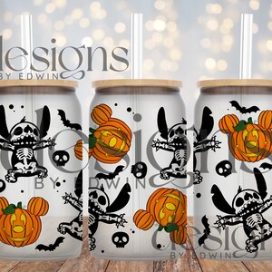 May include: Three white can-shaped tumblers with black lids and clear straws. Each tumbler features a Halloween-themed design with a black and white skeleton Stitch character, a pumpkin with Mickey Mouse ears, and bats. The tumblers are on a blurred background.
