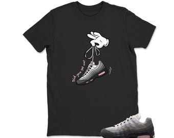 May include: Black t-shirt featuring a cartoon hand holding a sneaker by its laces. The sneaker is gray, black, and pink. The text "Did you get em?" is written in pink cursive. A matching sneaker is at the bottom.