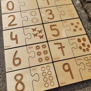 May include: Wooden puzzle pieces with numbers 0 through 9, each piece has a corresponding number of symbols, such as hearts, stars, flowers, and circles.