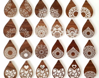 Op de afbeelding: Vierentwintig houten, traanvormige oorbellen met ingewikkelde witte ontwerpen. De ontwerpen omvatten mandala's, harten en andere patronen.