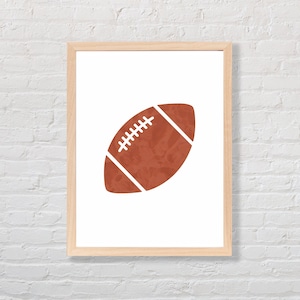 Puede incluir: Una impresi&oacute;n enmarcada de una pelota de f&uacute;tbol marr&oacute;n sobre un fondo blanco. La pelota de f&uacute;tbol es una silueta simple con costuras blancas.