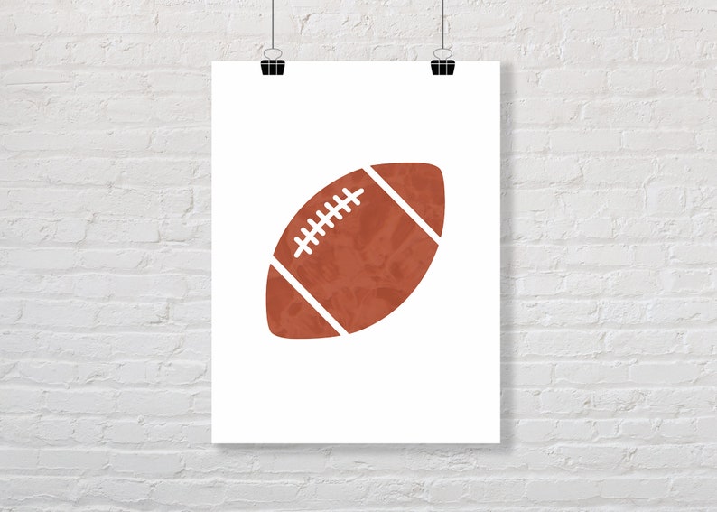 Puede incluir: Una ilustraci&oacute;n de una pelota de f&uacute;tbol marr&oacute;n y blanca sobre un fondo blanco. La pelota de f&uacute;tbol es una silueta simple con una apariencia texturizada.