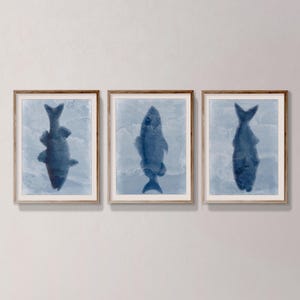 Peut inclure: Trois impressions encadrées de silhouettes de poissons bleus sur fond blanc. Les poissons sont tournés vers le haut et semblent nager dans une aquarelle bleu et blanc.