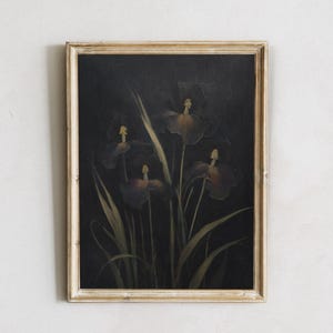 Puede incluir: Una pintura enmarcada de iris de color púrpura oscuro sobre un fondo negro. Las flores están dispuestas en un jarrón y los tallos son visibles. La pintura está en un marco blanco simple.