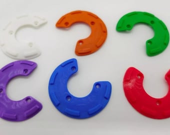 Op de afbeelding: Zes C-vormige ringen van plastic in verschillende kleuren: wit, oranje, groen, paars, blauw en rood. De ringen hebben een getextureerd oppervlak en zijn ontworpen om te worden gebruikt als decoratief element of voor een knutselproject.