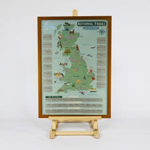 May include: A framed scratch map of UK National Parks, presented on a wooden easel. The map has a green and blue design, with illustrations of landmarks and wildlife. Text includes "National Parks" and a list of locations to scratch off.